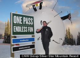Marke Dickson in front of the World's largest snowball adorned with skis, boards and hockey sticks.