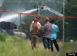 LAC-MEGANTIC QC - JULY 7: Towns people stand on the tracks leading to the derailed train in Lac-MÈgantic Sunday afternoon as firefighters continue to douse the smouldering tankers with water. Five people have now been declared dead and dozens remain missing after a train derailment caused a massive explosion in the quaint Quebec town of Lac-MÈgantic. (Lucas Oleniuk/Toronto Star via Getty Images)