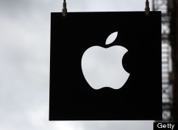 The Apple logo hangs in front of an Apple store