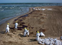 Relief workers shovel oiled sand into plastic bags at Grand Isle State Park, Louisiana, June 5, 2010.