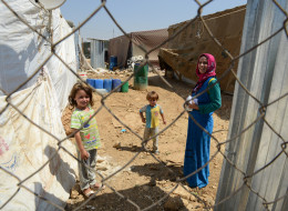 ZAHLE, LEBANON - SEPTEMBER 5, 2013: A Syrian refugee woman seen with her children behind the fence while holding medication after visiting the clinic in Dalhamieh settlement in Bekaa valley in Zahle on September 5, 2013. This health care is sponsored by UNICEF and executed by Lebanese non governmental organization (NGO) called Beyond Association. (Photo by Kaveh Kazemi/Getty Images)
