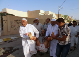 Iraqis carry a wounded man at the scene of a car bomb attack after it exploded as worshippers left a Sunni mosque following prayers marking the start of the Eid al-Adha Muslim holiday in the northern Iraqi city of Kirkuk on Oct. 15, 2013. (Photo by MARWAN IBRAHIM/AFP/Getty Images)