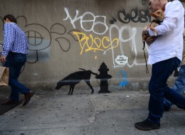 People walk by a street art graffiti by elusive British artist Banksy, as part of his month-long Better Out Than In exhibit, in New York, October 3, 2013. Banksy will be attempting to host an entire show on the streets of New York during a month residency. (EMMANUEL DUNAND/AFP/Getty Images)