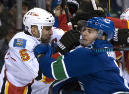 Vancouver Canucks left wing Alex Burrows (14) wrestles with Calgary Flames defenscman Mark Giordano (5) during the first period of NHL action in Vancouver on Saturday.
