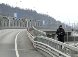 A police officer stands guard along the road between the mountain and coastal venues for the 2014 Winter Olympics, Wednesday, Feb. 5, 2014, outside of Sochi, Russia. (AP Photo/Charlie Riedel)