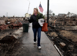 NEW YORK, NY - DECEMBER 07: Sheila Scandole recovers plants and an American flag for her boyfriend in the hard hit Breezy Point neighborhood on December 7, 2012 in the Queens borough of New York City. Breezy Point, home to many New York City firefighters and police, lost 111 homes in a fast moving fire during Superstorm Sandy with many more homes severely damaged from flooding. (Photo by Mario Tama/Getty Images)