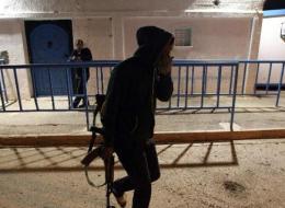 Un homme armé passe devant le consulat de Tunisie à Benghazi, 22 février 2014