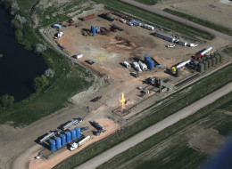 In this June 12, 2014 aerial photo, drivers and their tanker trucks, capable of hauling water and fracking liquid line up near a natural gas burn off flame and storage tanks in Williston, N.D. (AP Photo/Charles Rex Arbogast)