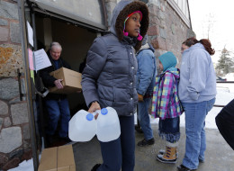 In this Tuesday, Feb. 3, 2015 photo, Genetha Campbell carries free water being distributed at the Lincoln Park United Methodist Church in Flint, Mich, Since the financially struggling city broke away from the Detroit water system last year, residents have been unhappy with the smell, taste and appearance of water from the cityâs river as they await the completion of a pipe to Lake Huron. They also have raised health concerns, reporting rashes, hair loss and other problems. A General Motors 