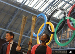 Sebastian Coe, Chairman of the London Organizing Committee for the 2012 Olympic games, left, and former British athlete Denise Lewis hold up the relay torches as it is unveiled in central London, Wednesday, June, 8, 2011. The torch for the 2012 London Olympics has been revealed, a golden aluminum tube featuring a lace-like mesh with 8,000 holes that represent the number of bearers and how many miles it will travel in the 70-day relay across Britain. (AP Photo/Alastair Grant)