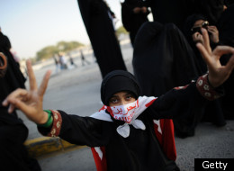 Covered her face by a Bahrain flag, a Shiite Muslim woman flashes victory signs during funeral of Ali al-Qassab, a demonstrator who was killed during the clashes with the security forces in Abu Saiba Village on December 17, 2011. (Getty)