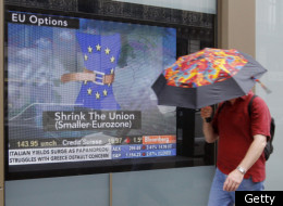 A man holding an umbrella passes by a TV screen showing a Bloomberg television channel's news program in a window on September 12, 2011 in Paris. (Getty)