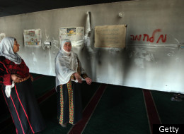 A Palestinian women gestures in front of a wall with Hebrew graffiti inside a mosque which extremists torched and vandalized in the village of Burka near Ramallah on December 15, 2011, in the latest 'price tag' vengeance attack. (Getty)