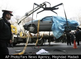 People gather around a car as it is removed by a mobile crane in Tehran, Iran, Wednesday, Jan. 11, 2012. Two assailants on a motorcycle attached magnetic bombs to the car of an Iranian university professor working at a key nuclear facility, killing him and wounding two people on Wednesday, a semiofficial news agency reported.
