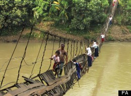 Indonesian children cling onto the rails to cross the river