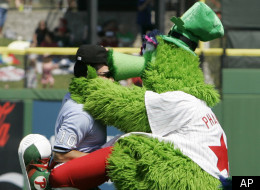 The Philadelphia Phillies mascot the Phillie Phanatic kisses third base umpire Phil Cuzzi between innings against the Cleveland Indians during a Grapefruit League spring training baseball game in Clearwater, Fla., Monday, March 17, 2008. (AP Photo/Paul Sancya)