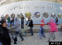 Fans walk by a wall decorated with football helmets as others stop to take pictures at the Super Bowl Village on Saturday, Jan. 28, 2012, in Indianapolis. Super Bowl Village includes activities, attractions and music in conjunction with Super Bowl XLVI, which will feature the New England Patriots facing the New York Giants on Feb. 5. (AP Photo/Mark Humphrey)
