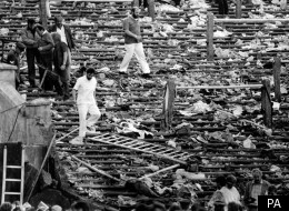 Shocked spectators walk through the personal belongings of victims littering the stands, after the disaster at Heysel Stadium in Brussels