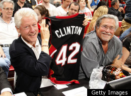 President Bill Clinton shows off a new Miami Heat jersey as he takes in a game with Heat owner Mickey Arison.