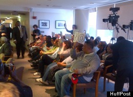 Audience members at a Detroit City Council meeting April 2, 2012, hold signs protesting a possible financial consent agreement between the city and state of Michigan.