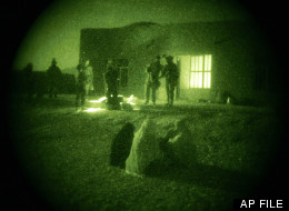 In this Oct. 28, 2009 file photo taken with a night vision scope, Afghan women and their children wait as U.S. Special Operations forces and Afghan National Army soldiers search their home during a joint operation targeting insurgents operating in Afghanistan's Farah province. (AP Photo/Maya Alleruzzo, File)