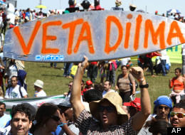 A demonstrator holds up a surfboard spray painted with a message in Portuguese that reads: