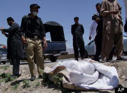 Pakistani security officials stand next to covered body of British Red Cross worker Khalil Rasjed Dale at the site in Quetta, Pakistan on Sunday, April 29, 2012. (AP Photo/Arshad Butt)