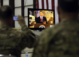 Military personnel watch on a screen as President Barack Obama makes a live address at Bagram Air Field, Afghanistan, Wednesday, May 2, 2012. (AP Photo/Charles Dharapak)