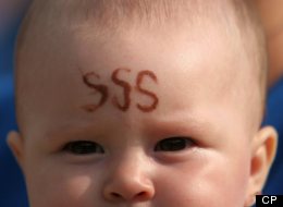 A member of Growing in Grace, a Florida-based controversial religious sect, holds a baby with the letters