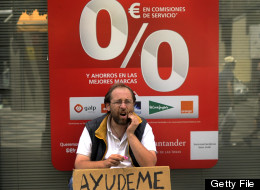 A man holding a cardboard reading ''help me'' asks for money in front of a bank in Madrid, on Juny 9, 2012. Spain has not changed its position and is not seeking aid for its banking sector, an economy ministry spokeswoman said on June 9 ahead of a conference call by eurozone finance ministers. (EDRO ARMESTRE/AFP/GettyImages)