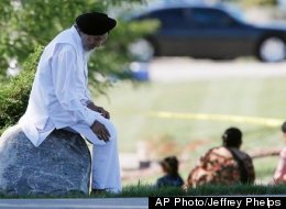 A man sits on a rock as police investigate the Sikh Temple of Wisconsin in Oak Creek, Wis., after a shooting Sunday, Aug 5, 2012. The intentions of the gunman, Wade Page, may forever elude authorities.
