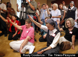 Attendees hold their hands up during a blessing by Archbishop Gregory Aymond, during the opening of the Magnificat House of Discernment for Women in New Orleans, Louisiana, Wednesday, August 15, 2012.