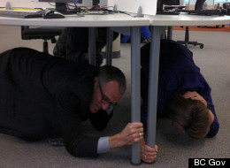 Minister of Justice and Attorney General Shirley Bond takes cover under a desk during B.C.'s ShakeOut earthquake drill on Oct. 18, 2012. (B.C. Government)