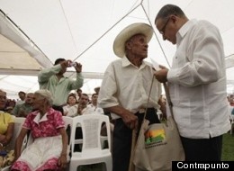 Un anciano recibe cien dólares de manos del presidente salvadoreño Mauricio Funes.