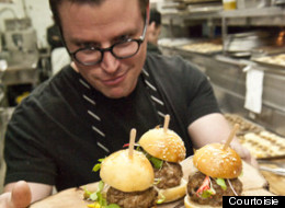 Le chef invité Danny St-Pierre tient les mini burgers de ragoût de boulettes et pattes de cochon